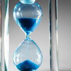 Blue hourglass on gray background close up
